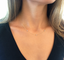 Delicate three-stone cubic zirconia gold necklace worn with a black V-neck