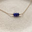 Necklace with blue sapphire beads on a gold chain against a beige background