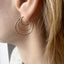 Close-up of a person wearing a gold hoop earring with a blurred background