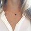 A model is wearing a sapphire heart shaped necklace layered with a minimalist circle necklace sold together as a layered necklace set.