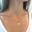 Gold initial disc necklace with ruby charms worn on the collarbone with a white tank top