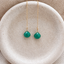 Emerald threader earrings in 14k gold filled with faceted emerald briolette drops on a fine chain, on a speckled ceramic dish - Lolabean