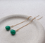 Gold filled emerald threader earrings with faceted green emerald drops laid on a stoneware dish