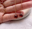 Pair of garnet threader earrings held in hand to show the size of the garnet drops