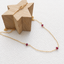 Gold-filled garnet station necklace draped over a wooden star showing the spring ring clasp