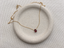 Gold-filled garnet teardrop necklace with spring ring clasp on a speckled ceramic dish