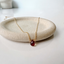 Deep red garnet teardrop necklace in 14k gold-filled, January birthstone, on a stoneware dish