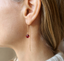 Side view of a garnet threader earring worn with a sweater