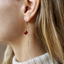Close-up of a garnet threader earring worn on the ear