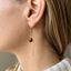 Garnet threader earring worn on the ear, showing the garnet drop and threader chain