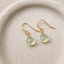 Prehnite heart drop earrings in 14k gold-filled on a speckled ceramic dish