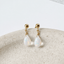 Gold filled opal teardrop stud earrings on a speckled ceramic dish