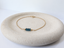 14k gold-filled London blue topaz bracelet with three faceted deep blue rondelles on a cream ceramic dish