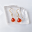 Gold-filled carnelian heart drop earrings on a clear crystal slab
