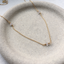 Gold-filled cubic zirconia station necklace with three faceted CZ rondelles on a speckled ceramic dish
