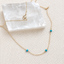 Gold filled turquoise station necklace with spring ring clasp draped over a selenite slab, showing three wire-wrapped turquoise beads