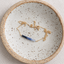 Gold-filled ombré sapphire necklace coiled in a speckled ceramic dish