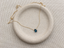 Gold-filled London blue topaz briolette necklace with spring ring clasp on a round ceramic plate