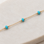 Close-up of faceted turquoise beads hand wire-wrapped on a 14k gold-filled chain bracelet on white marble