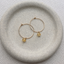 Gold citrine hoop earrings on a stone dish