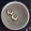 Gold hoop earrings on a beige ceramic dish