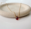 Dainty garnet teardrop necklace in 14k gold-filled with a faceted garnet briolette on a stone dish