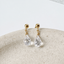 Gold-filled cubic zirconia teardrop stud earrings on a ceramic dish
