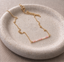 Gold filled pink opal beaded bar necklace on a speckled ceramic dish