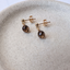 Pair of gold-filled smoky quartz stud earrings in a stone dish