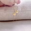 Gold filled citrine paperclip threader earrings held against a linen pillow