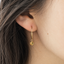 Close-up of a gold gemstone hoop earring with golden citrine