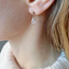 Cubic zirconia teardrop stud earring worn with a soft sweater