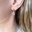 Close-up of a dainty gold-filled cubic zirconia drop stud earring on the ear