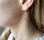 Close-up of a citrine teardrop paperclip threader earring on the ear