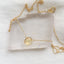 Gold necklace with a yellow citrine gemstone on a white background