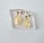Gold earrings with citrine stone on a light gray background