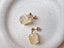 Pair of gold earrings with natural citrine gemstone designs on a textured surface