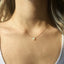 Gold necklace with a small opal pendant on a person's neck