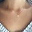 Necklace with a small opal pendant worn by a person, close-up view.