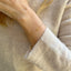 Close-up of a person wearing a gold citrine bracelet on a light-colored sweater.