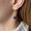 Close-up of an ear wearing a blue sapphire threader earring with a gold chain.