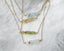 Three gold necklaces with beaded aquamarine, citrine, peridot, and moonstone beads on a white fabric background