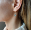 Close-up of a dainty labradorite drop earring worn on the ear