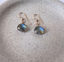 Gold labradorite dangle earrings on a ceramic plate