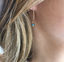 Close-up of a gold labradorite hoop earring worn on the ear