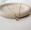 Labradorite teardrop necklace draped over a stone dish