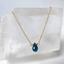 London blue topaz teardrop necklace in 14k gold filled displayed on a clear crystal slab