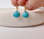 Close-up of faceted turquoise dangle earrings with natural matrix markings and gold filled ear wires