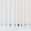 A group of dainty teardrop birthstone necklaces with faceted briolette gemstones on a natural background