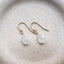     Pear shaped moonstone drop earrings with luminous white gemstones and delicate gold filled ear wires on a neutral background